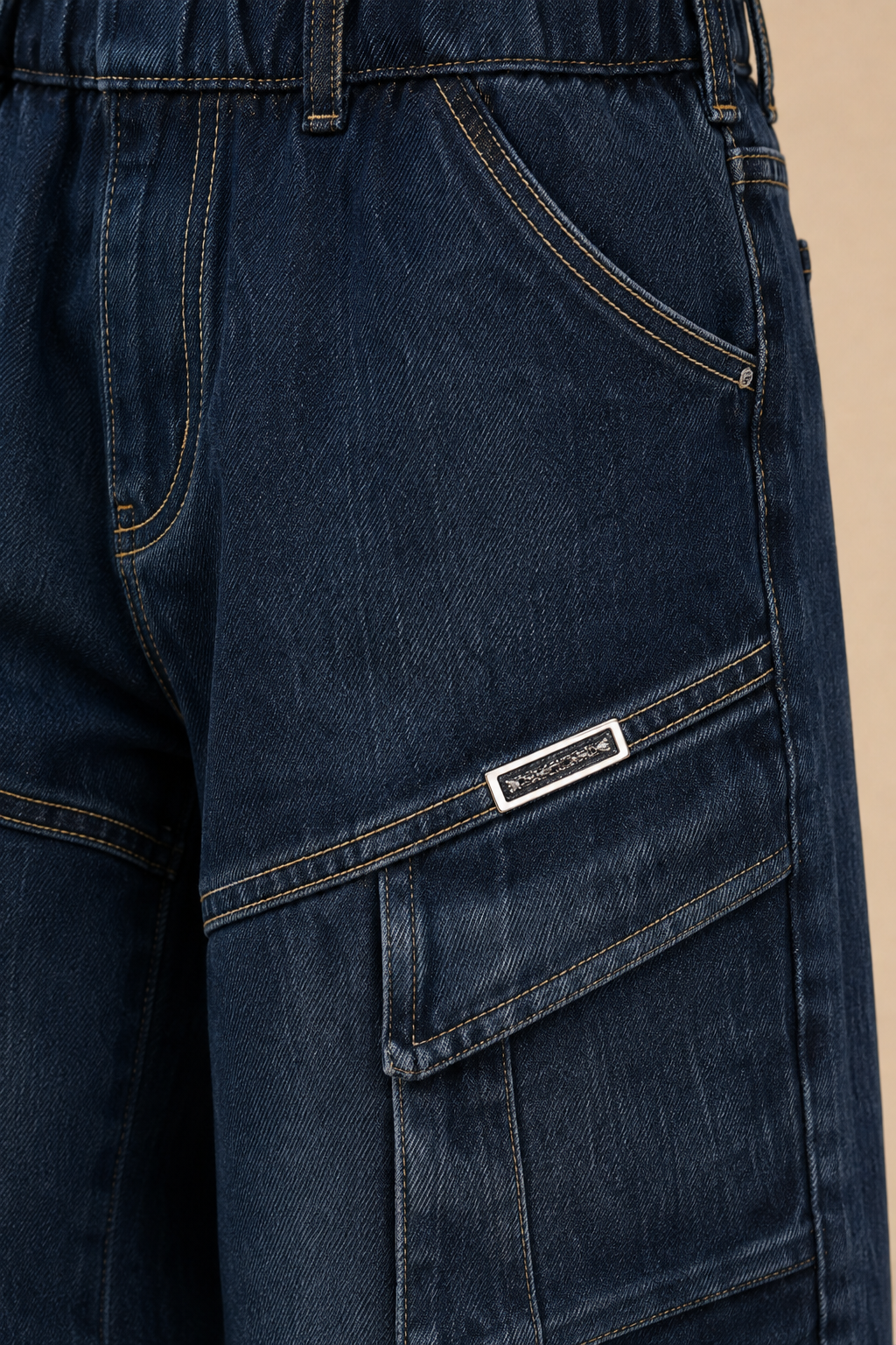 Close-up of dark blue denim cargo shorts showing the side pocket with a silver-tone brand tag that reads 'SUGARBOY'.