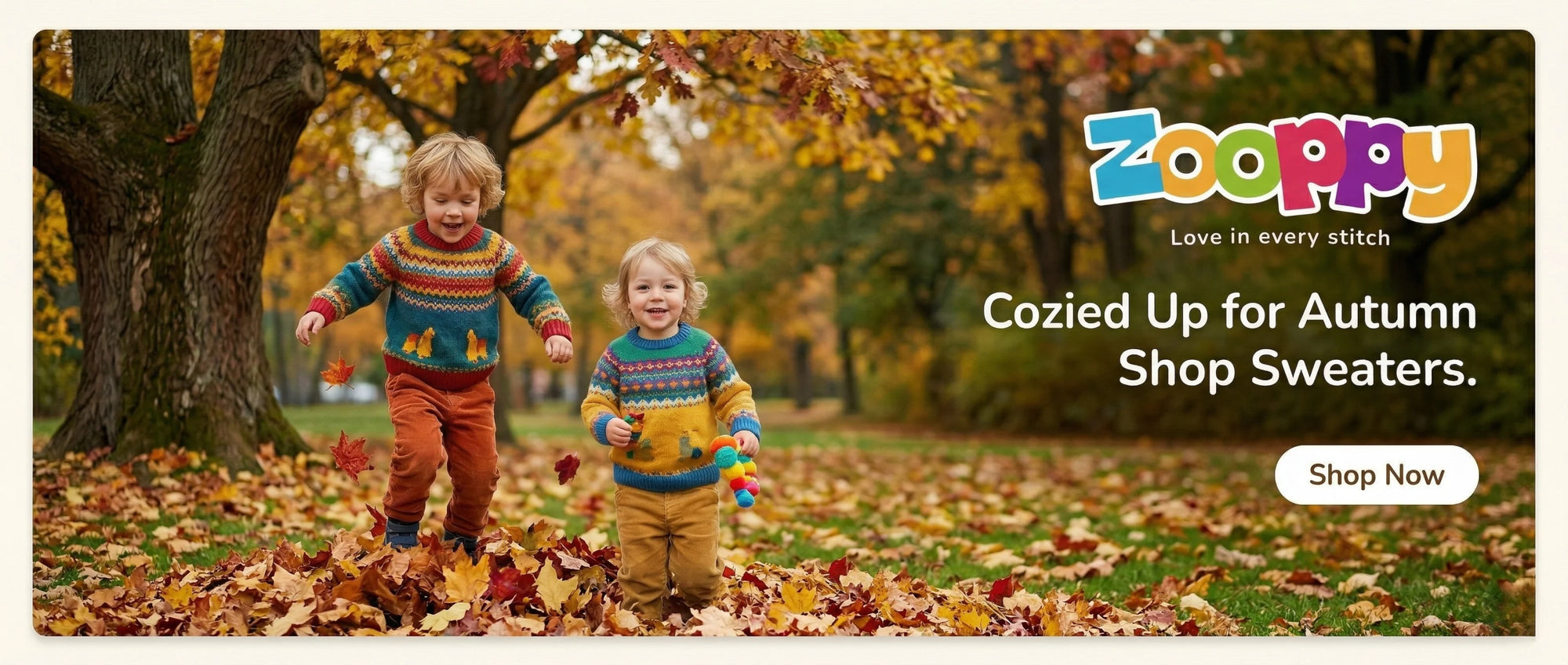 Two children in colorful sweaters standing in a leaf-covered park with Zooppy branding.